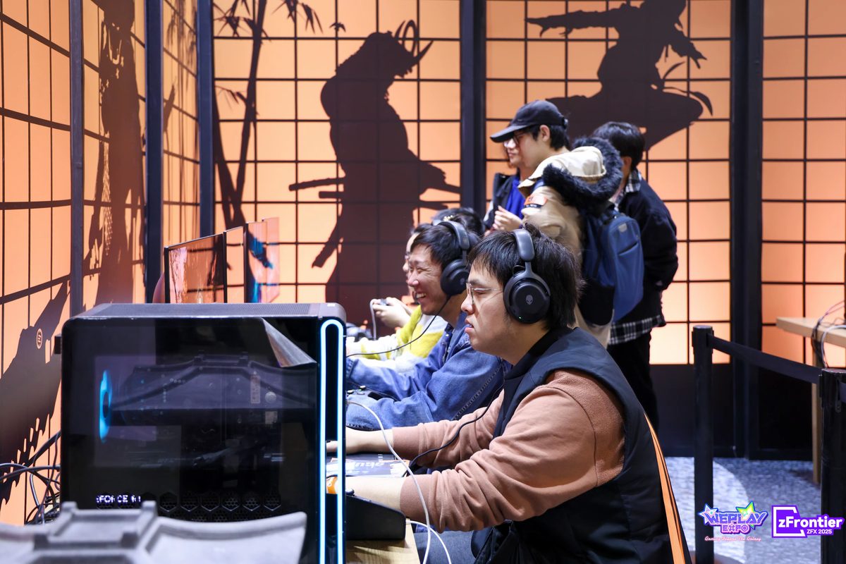 Visitors wearing headphones and trying games at a WePlay Expo demo booth
